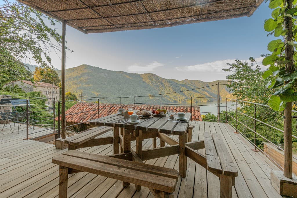 Petit-déjeuner servi sur la terrasse en bois, face au lac de Tolla et aux montagnes